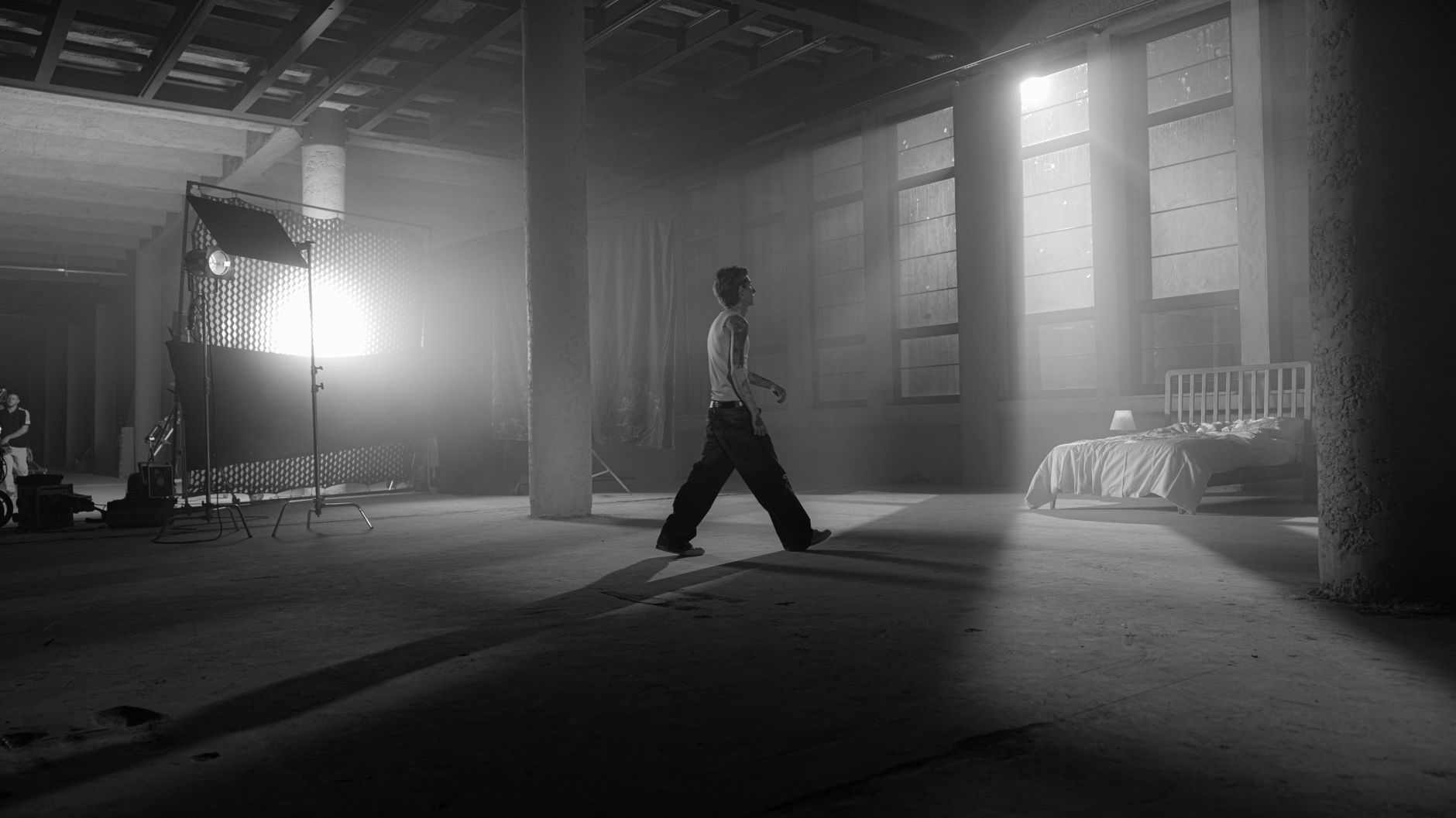 Schwarz-weißes Filmset mit Schauspieler, Scheinwerfern und Bettkulisse